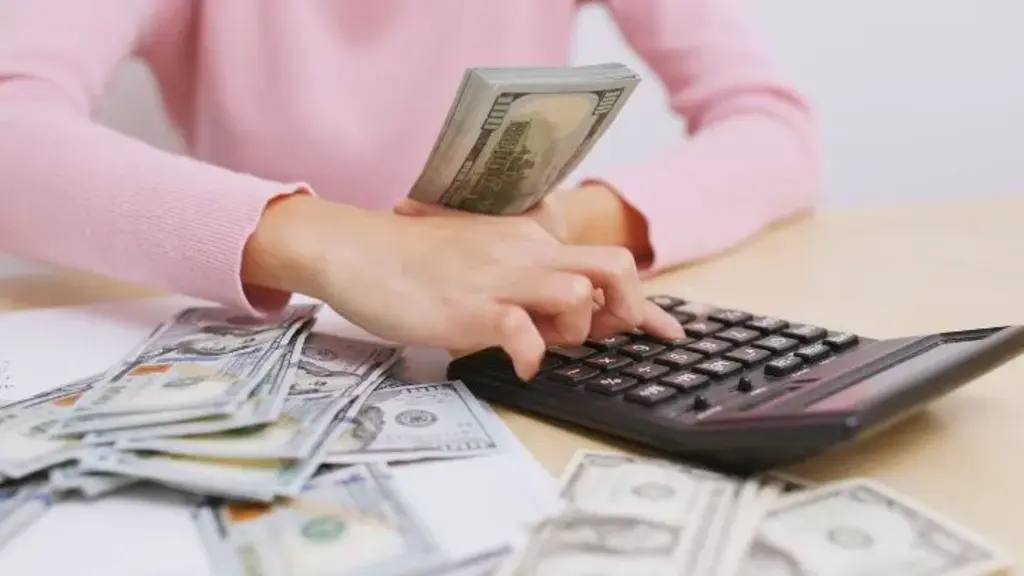 a person counting money on a calculator